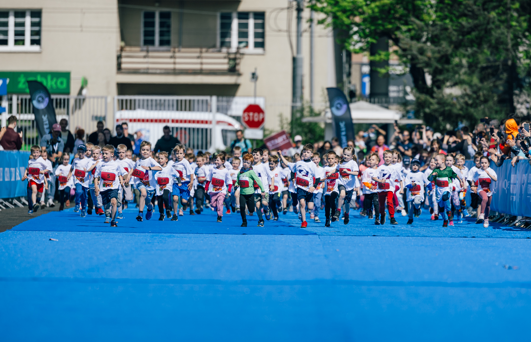 Grupa dzieci biegnie na terenie Międzynarodowych Targów Poznańskich