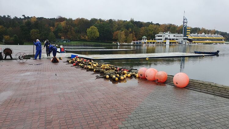 Na mecie toru regatowego pracownicy wyciągają boje na brzeg jeziora