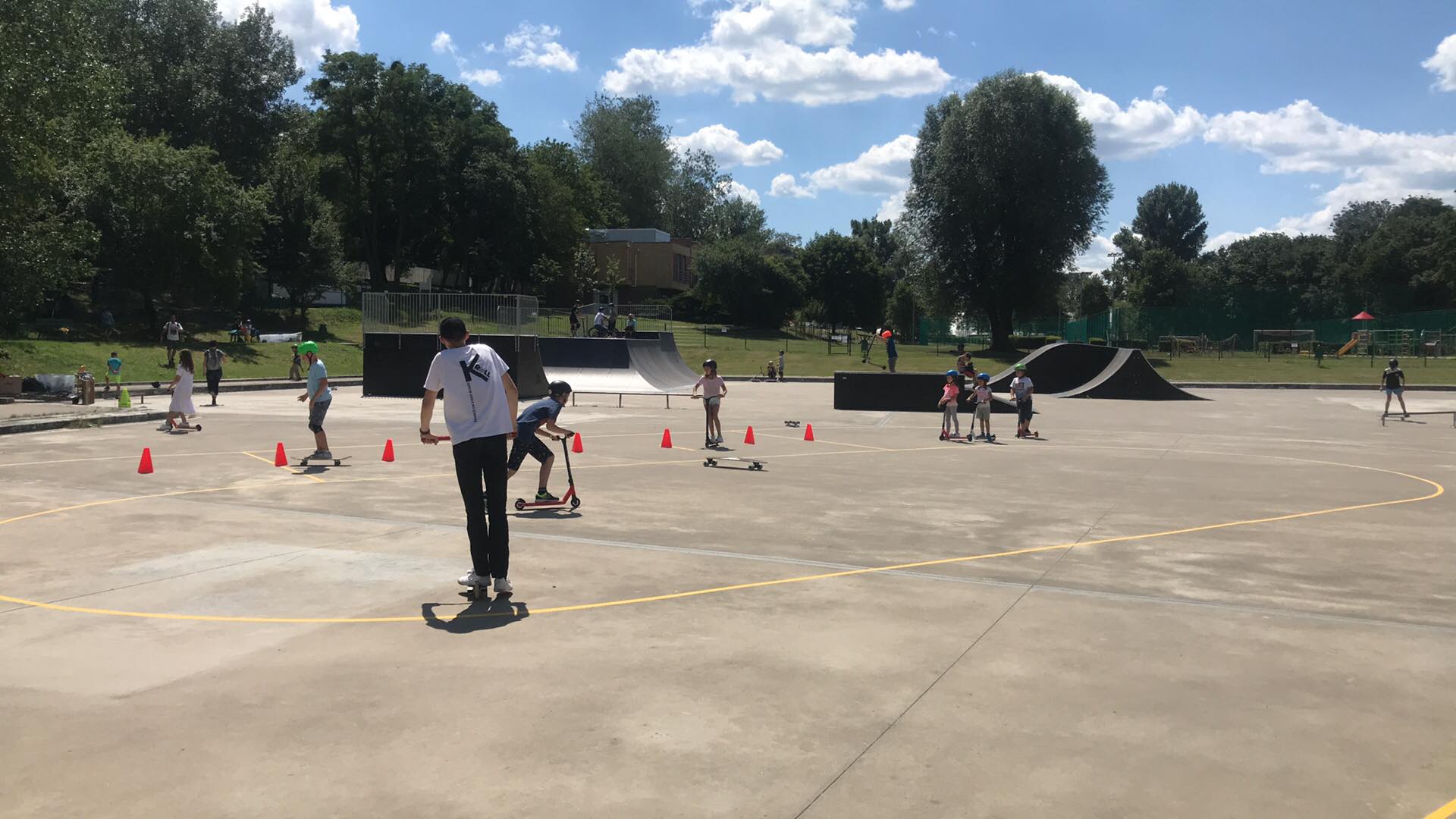 Dzieci jeżdżą na hulajnogach na terenie skateparku