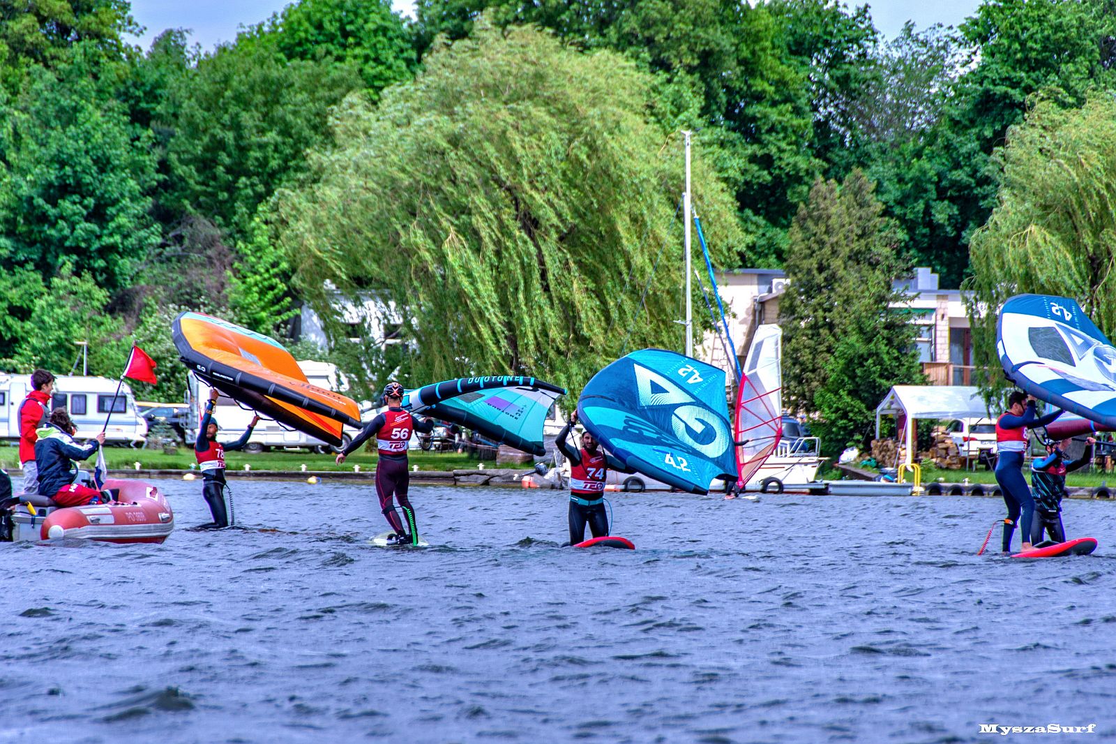 Zawodnicy na deskach windsurfingowych na jeziorze