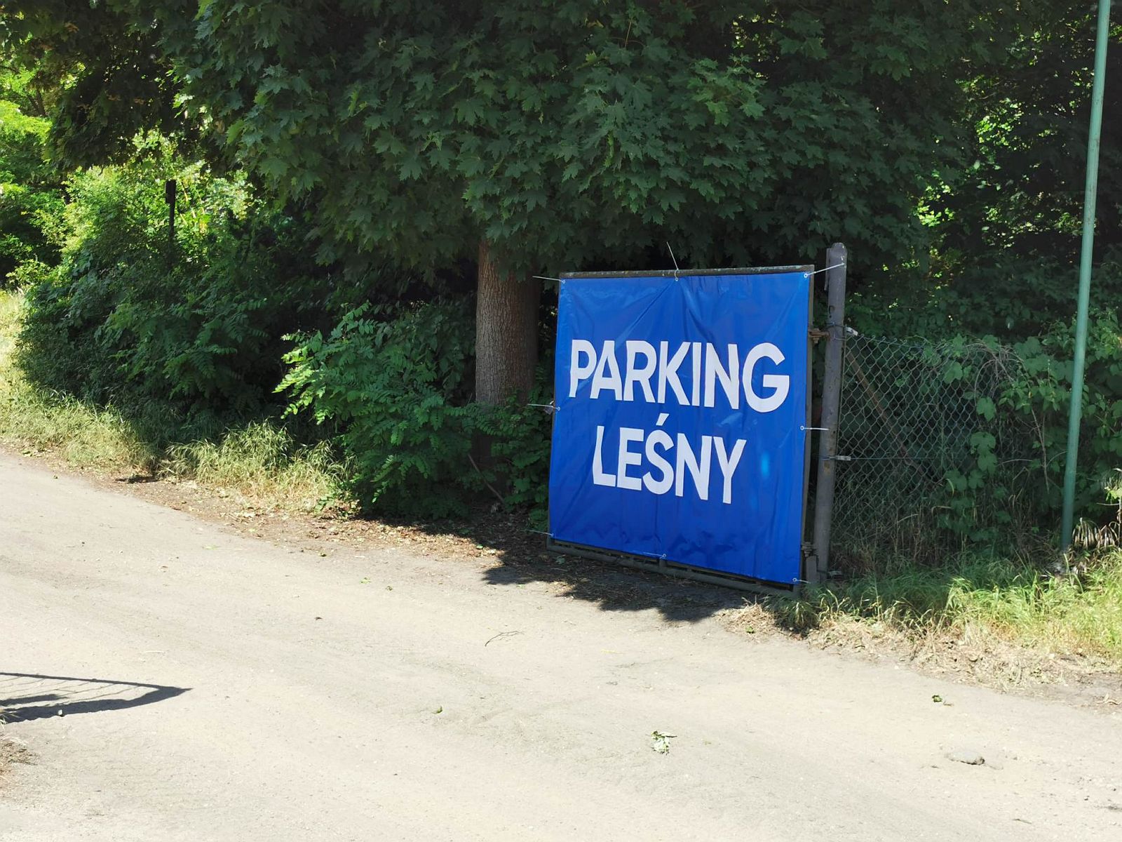 Rozwieszony na płocie baner z napisem Parking Leśny