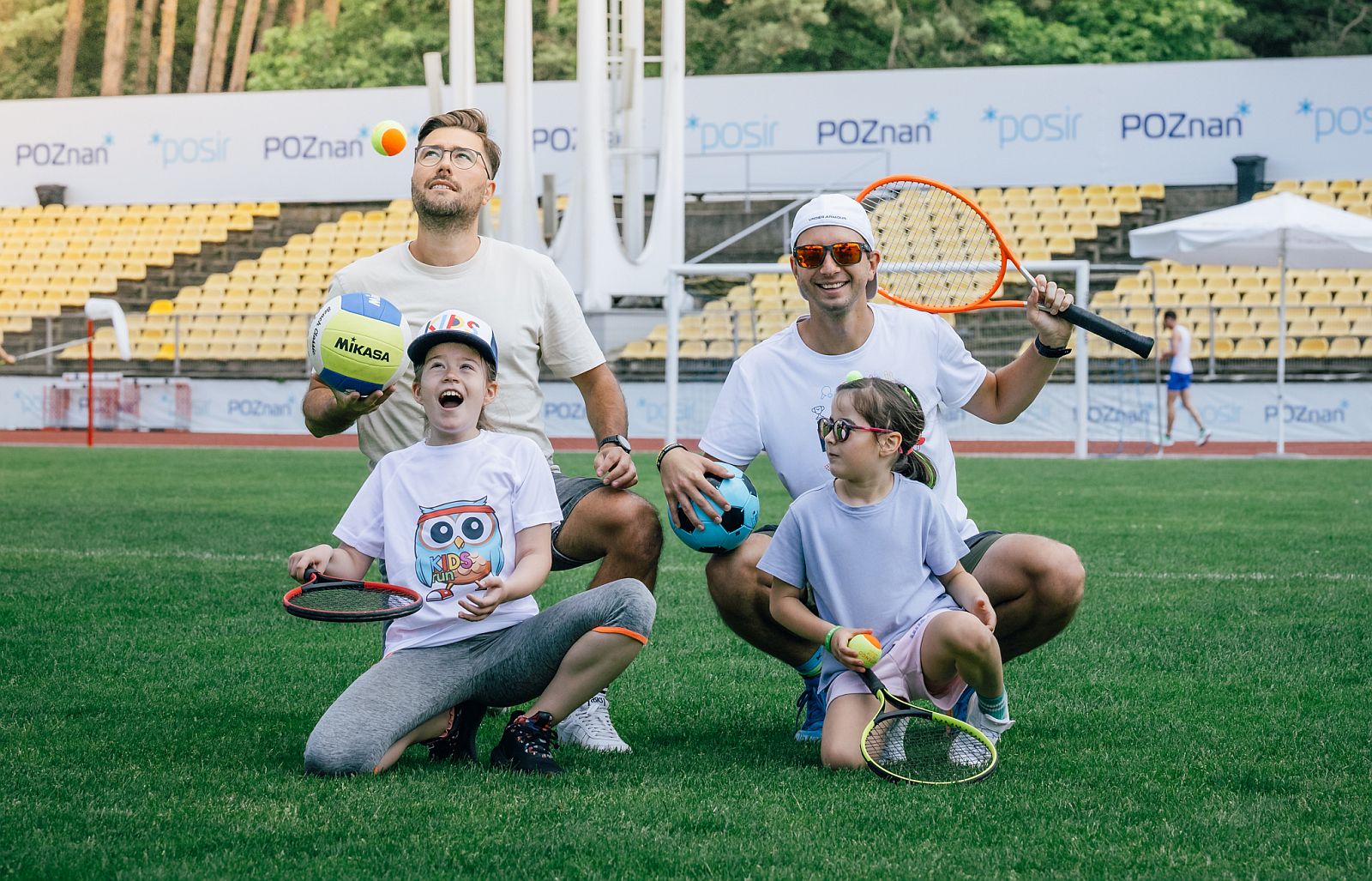 dwóch mężczyzn z dwójką dzieci na stadionie lekkoatletycznym