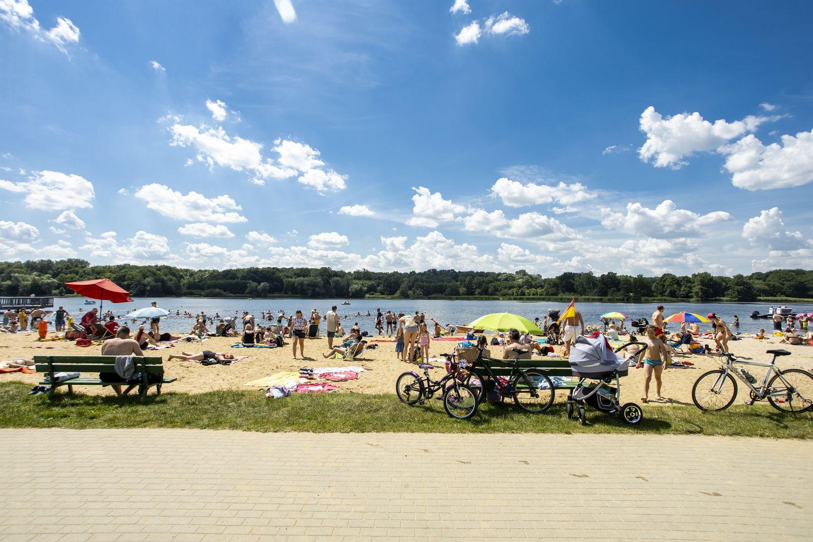 plaża nad Rusałką. Ludzie opalają się i kąpią w jeziorze