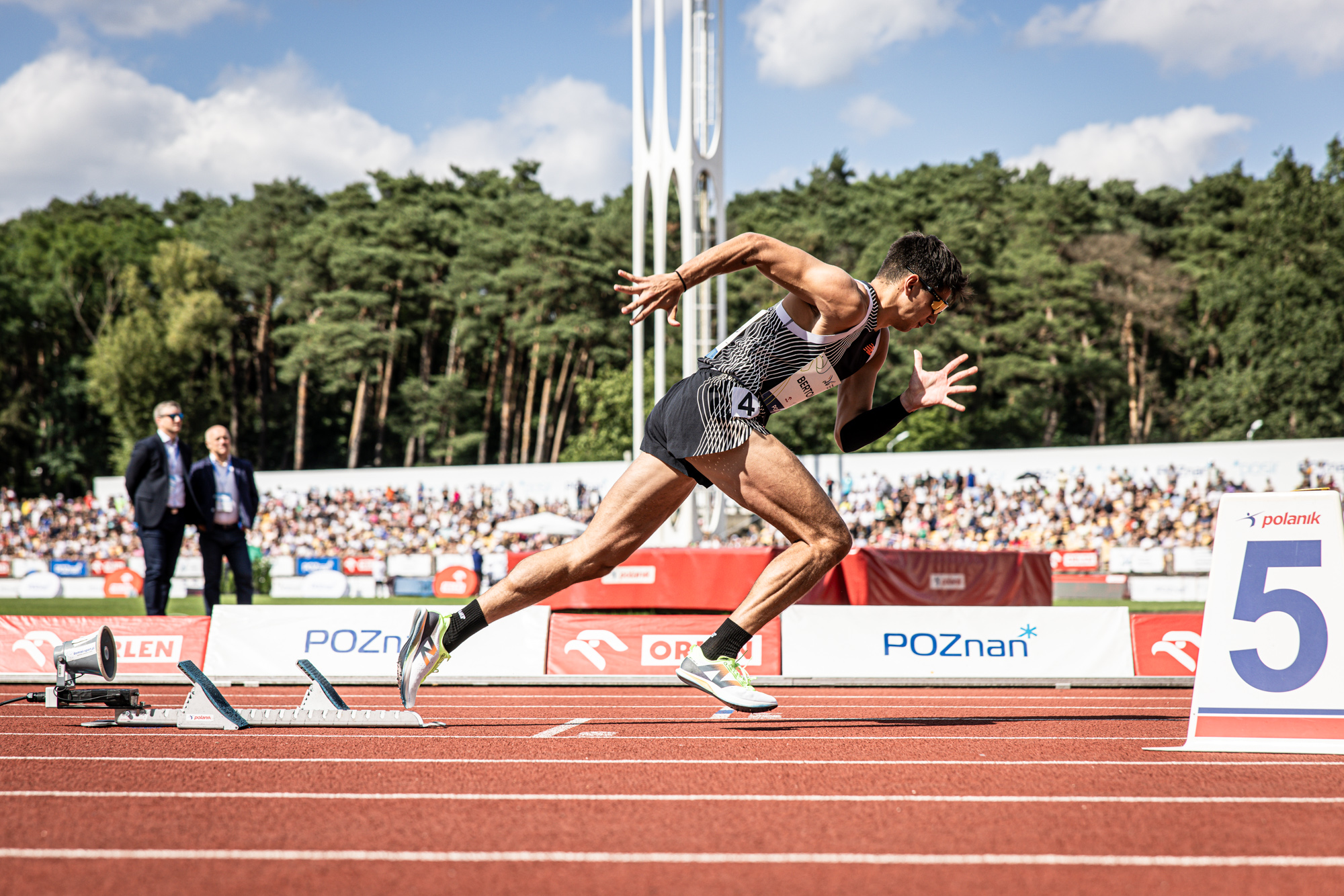 Sprinter wybiega z bloków startowych na bieżni lekkoatletycznej.