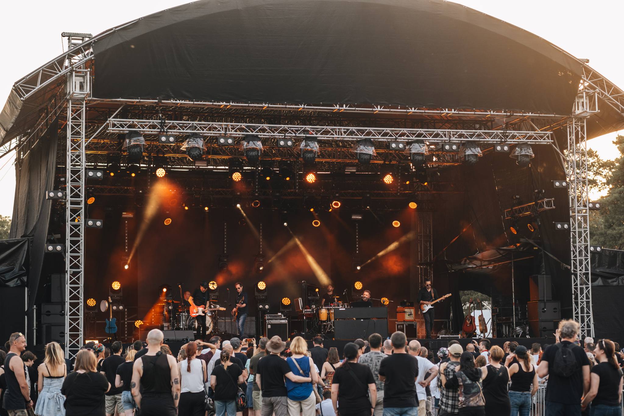 zdjęcie przedstawia ludzi przed sceną, którzy słuchają zespołu występującego podczas koncertu.