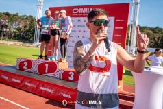 Tomasz-Smokowski-mowi-do-mikrofonu-w-tle-stoj-ludzie-na-podium