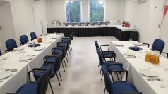 Sala konferencyjna duża z dwoma zastawionymi stołami. W głębi widać stół z potrawami
