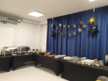 Sala konferencyjna duża z nakrytym stołem z potrawami. Urodzinowy wystrój sali. 