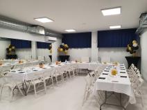 Sala konferencyjna duża z zastawionymi stołami, ozdobiona balonami.