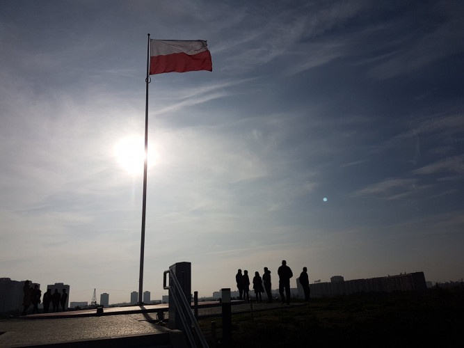 Ludzie na szczycie kopca, maszt z flagą