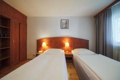 pokój hotelowy dwa pojedyncze łóżka, szafa oraz drzwi wejściowe